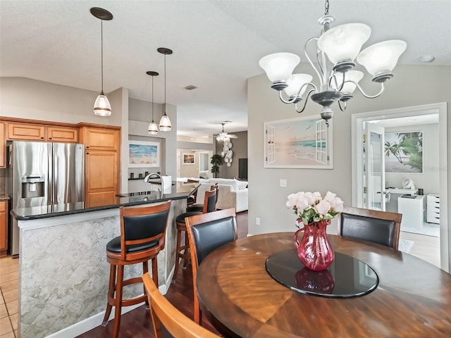 dining space featuring lofted ceiling, an inviting chandelier, sink, and tile patterned floors