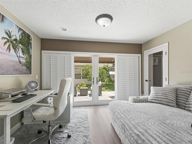 bedroom featuring a textured ceiling, access to exterior, hardwood / wood-style floors, and french doors