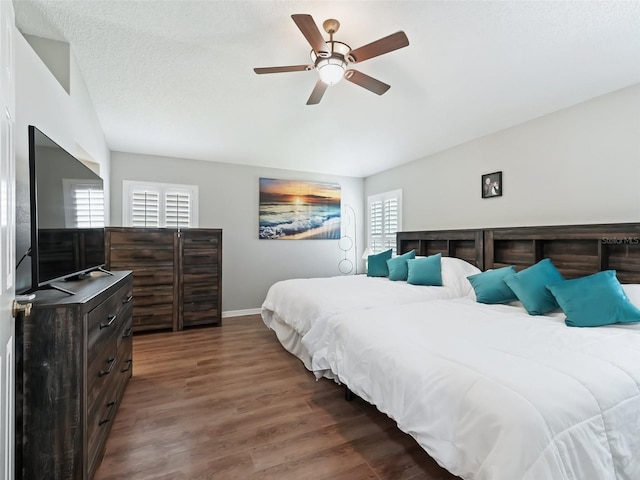 bedroom featuring multiple windows, a textured ceiling, ceiling fan, and dark hardwood / wood-style floors