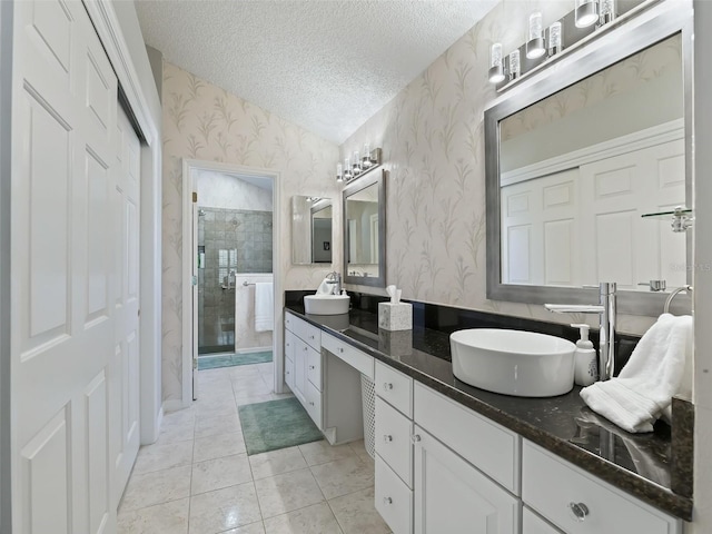 bathroom with vanity, a textured ceiling, tile patterned floors, and a shower with door