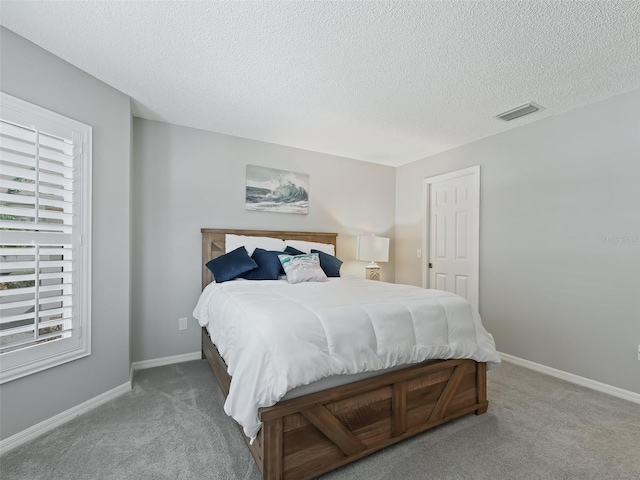 carpeted bedroom with multiple windows and a textured ceiling