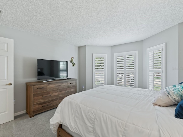 bedroom with multiple windows, light carpet, and a textured ceiling