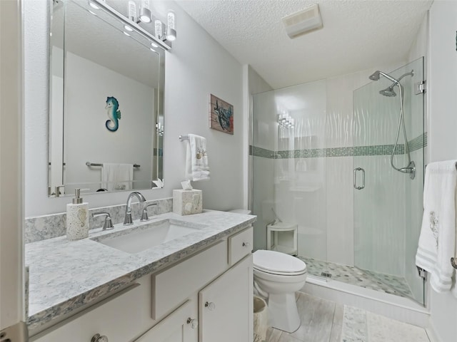 bathroom with vanity, toilet, an enclosed shower, and a textured ceiling