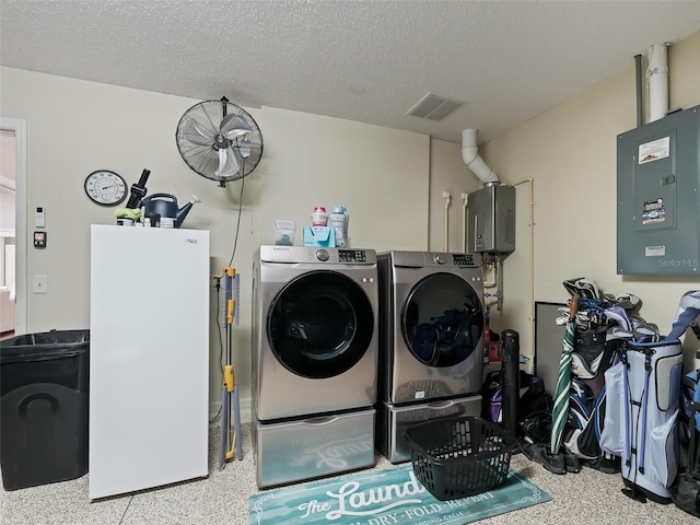 washroom featuring electric panel, a textured ceiling, and washer and dryer