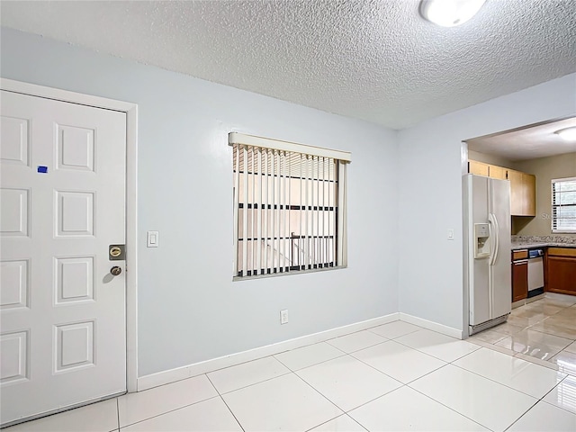 foyer entrance with a textured ceiling and light tile patterned floors