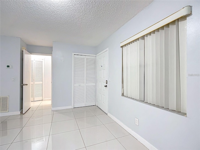 unfurnished bedroom with a textured ceiling, a closet, and light tile patterned floors