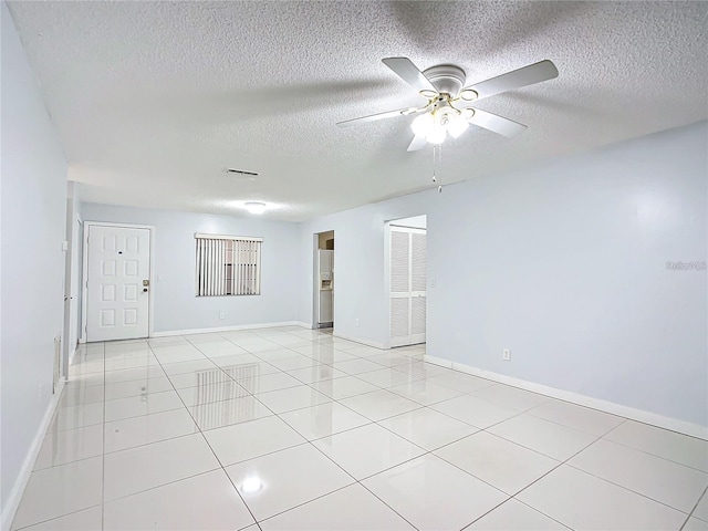 tiled empty room with ceiling fan and a textured ceiling