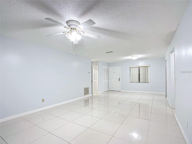 tiled empty room with ceiling fan and a textured ceiling