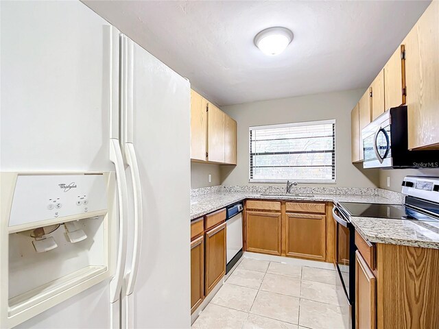 kitchen with sink, light tile patterned floors, light stone countertops, and stainless steel appliances