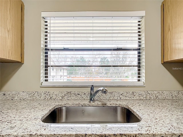 room details with sink, light brown cabinetry, and light stone counters