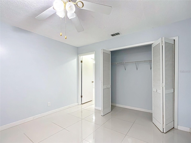 unfurnished bedroom with ceiling fan, a closet, a textured ceiling, and light tile patterned floors