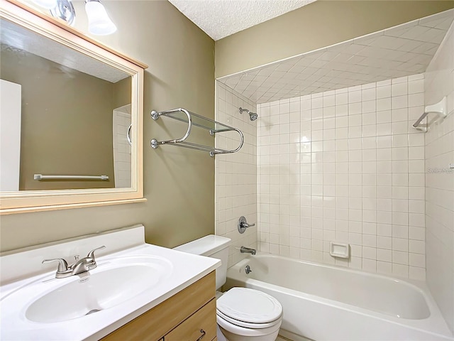 full bathroom with a textured ceiling, toilet, tiled shower / bath combo, and vanity