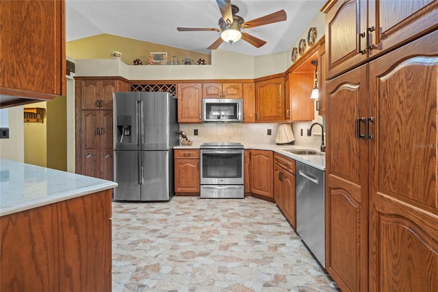 kitchen featuring decorative backsplash, appliances with stainless steel finishes, ceiling fan, sink, and lofted ceiling