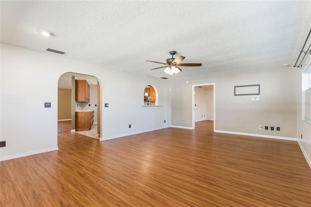 unfurnished room with ceiling fan, wood-type flooring, and a textured ceiling