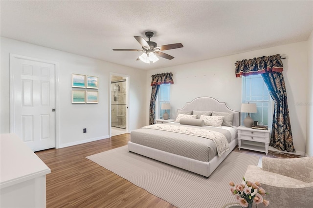 bedroom featuring hardwood / wood-style floors, connected bathroom, a textured ceiling, and ceiling fan