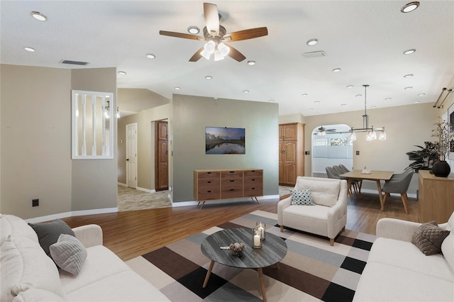 living room featuring vaulted ceiling, light hardwood / wood-style flooring, and ceiling fan