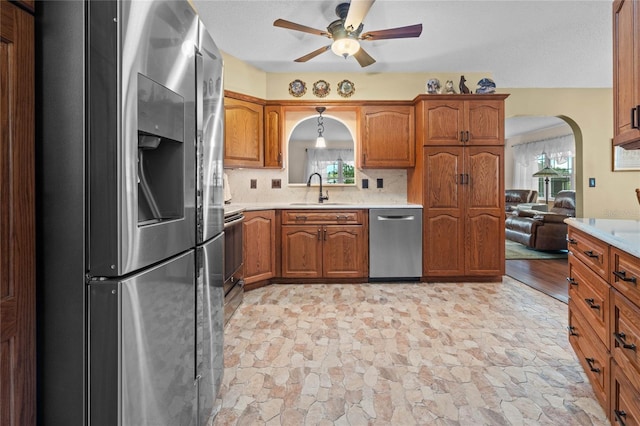 kitchen featuring ceiling fan, sink, stainless steel appliances, light hardwood / wood-style flooring, and backsplash