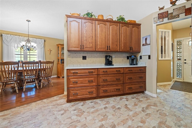 kitchen featuring tasteful backsplash, pendant lighting, light hardwood / wood-style floors, and an inviting chandelier