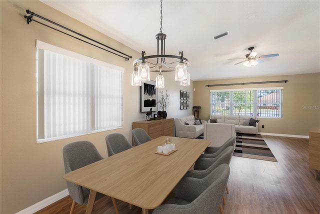 dining area with ceiling fan with notable chandelier and dark wood-type flooring