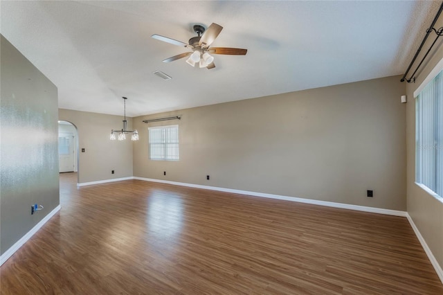 unfurnished room with ceiling fan with notable chandelier and dark wood-type flooring