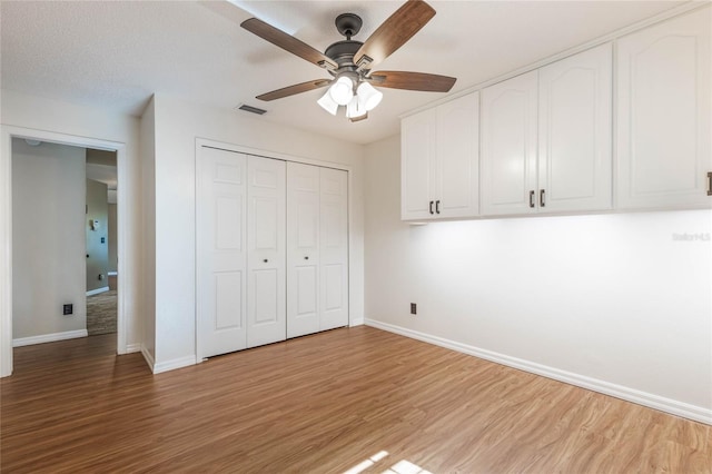 unfurnished bedroom featuring ceiling fan, a closet, a textured ceiling, and hardwood / wood-style flooring