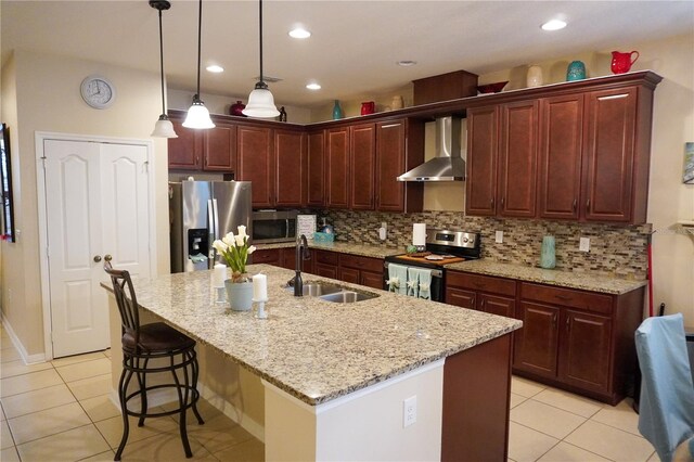 kitchen with tasteful backsplash, an island with sink, wall chimney exhaust hood, stainless steel appliances, and a sink