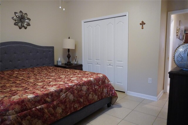 bedroom featuring light tile patterned floors, baseboards, and a closet