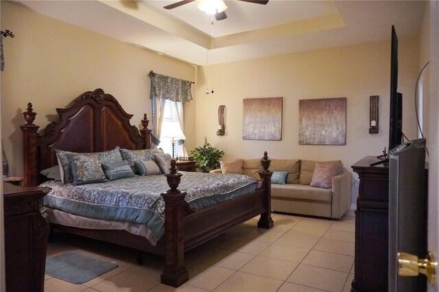 bedroom featuring a ceiling fan, a raised ceiling, and light tile patterned floors