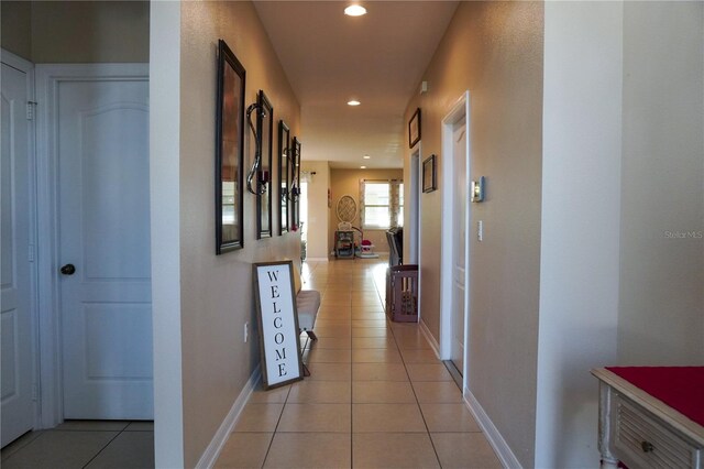 hall with light tile patterned floors, baseboards, and recessed lighting