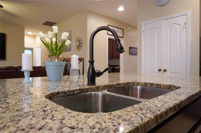 details with visible vents, light stone counters, a sink, and recessed lighting