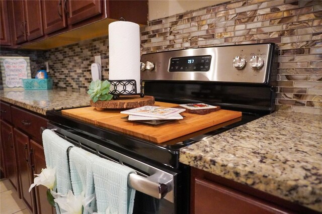 kitchen with light stone countertops, stainless steel range with electric cooktop, backsplash, and light tile patterned floors