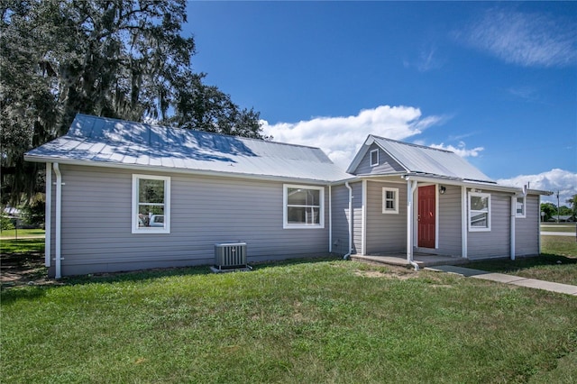 view of front of property with metal roof, a front lawn, and central AC