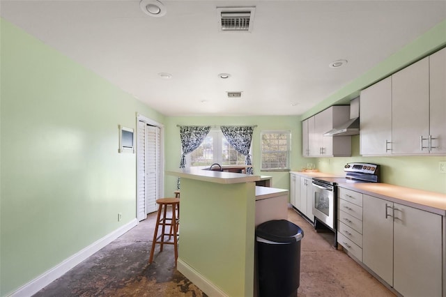 kitchen featuring stainless steel electric range, a kitchen bar, white cabinetry, and concrete floors