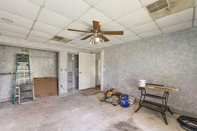 miscellaneous room with ceiling fan, concrete floors, and a paneled ceiling