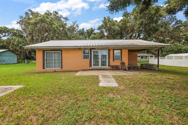 back of property with a yard, a patio, stucco siding, metal roof, and fence