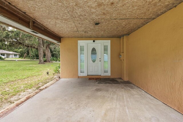 view of exterior entry with a lawn and stucco siding