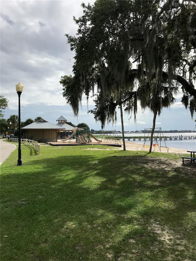 view of community featuring a playground, a water view, and a yard