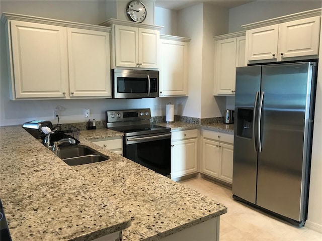 kitchen with light tile patterned floors, stainless steel appliances, sink, white cabinetry, and light stone counters