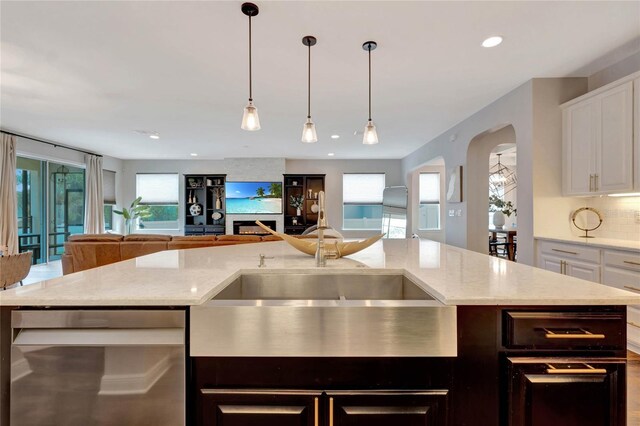 kitchen with white cabinets, a wealth of natural light, a center island with sink, and stainless steel dishwasher