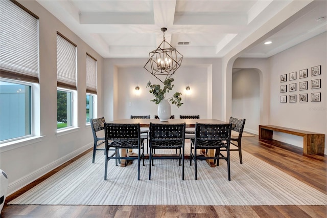 dining area with baseboards, visible vents, arched walkways, and wood finished floors