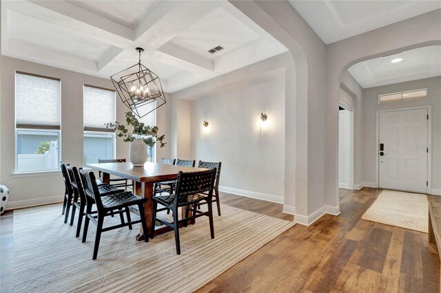 dining room with beamed ceiling, coffered ceiling, wood-type flooring, and a notable chandelier