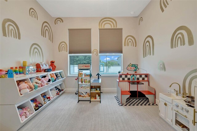 recreation room featuring light colored carpet and sink