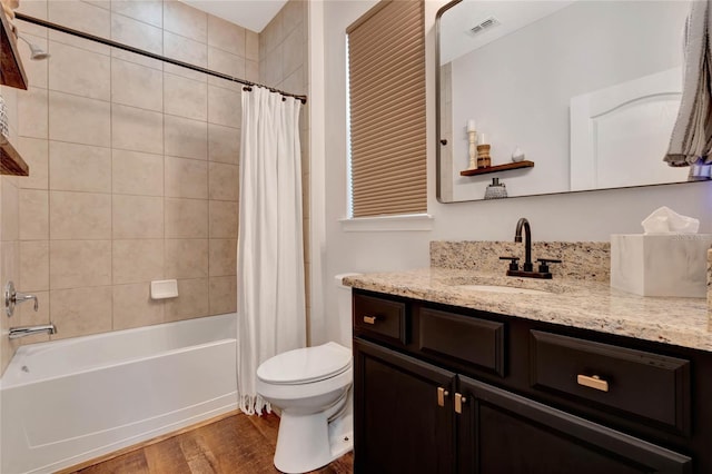 bathroom featuring visible vents, toilet, shower / tub combo, vanity, and wood finished floors