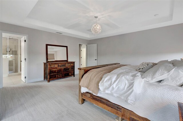 bedroom featuring a tray ceiling, ensuite bath, and light colored carpet