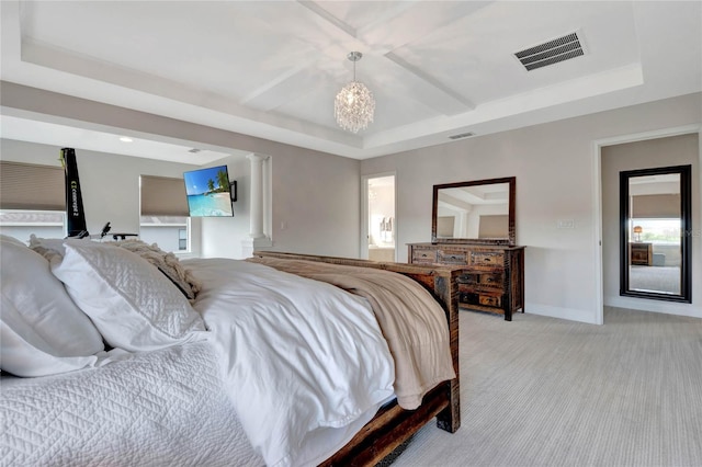 bedroom with a tray ceiling, ornate columns, light colored carpet, visible vents, and baseboards