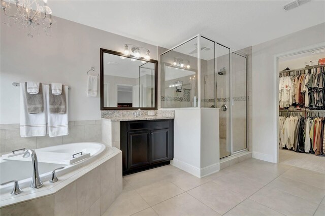 bathroom with vanity, a notable chandelier, tile patterned floors, and plus walk in shower