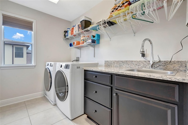 clothes washing area with cabinet space, light tile patterned flooring, a sink, separate washer and dryer, and baseboards