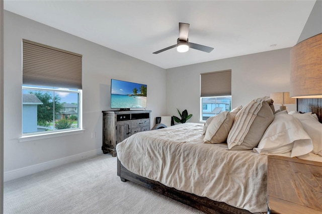 bedroom with light carpet, ceiling fan, and baseboards