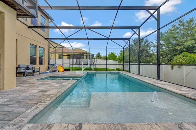 view of swimming pool featuring glass enclosure and a patio