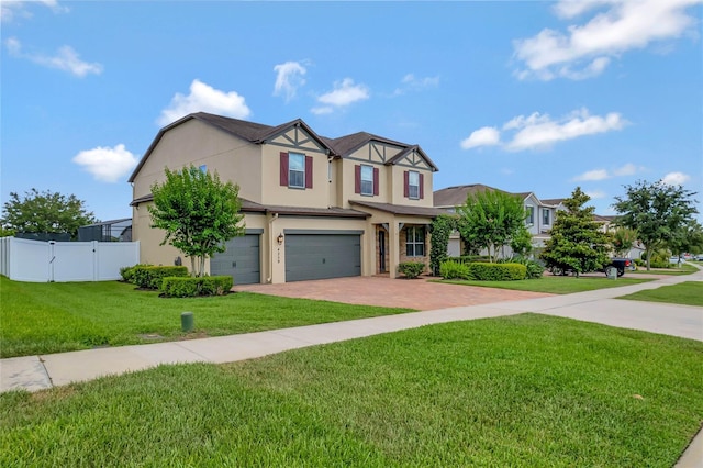 view of front of house with decorative driveway, stucco siding, fence, a garage, and a front lawn